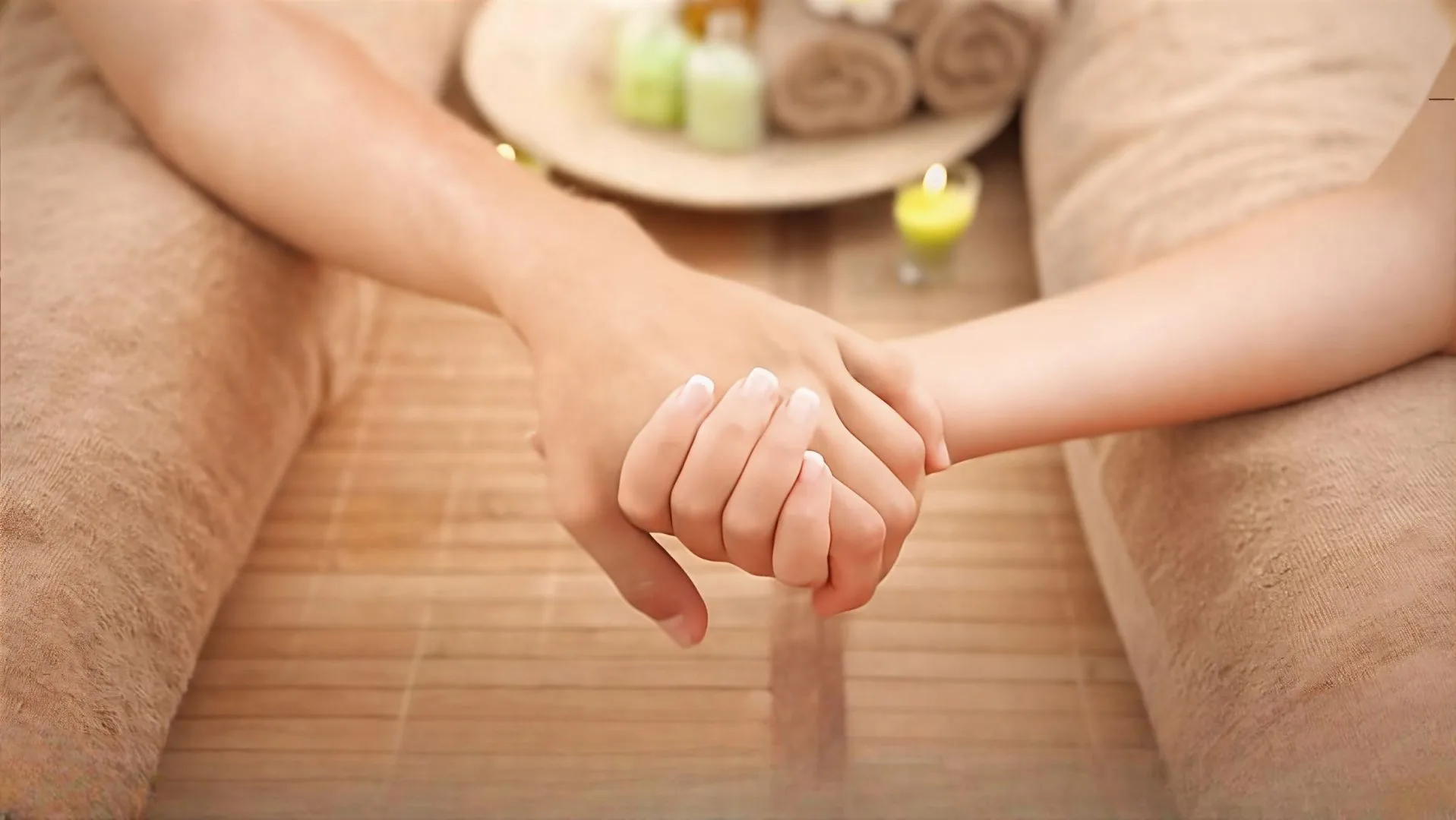Hand holding hand between 2 massage tables